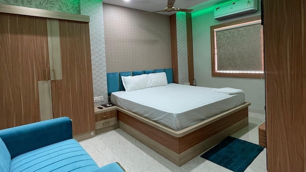 A modern bedroom with a bed, a nightstand, a blue chair, and a ceiling fan.