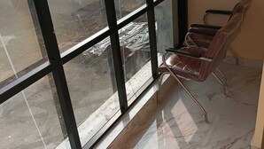 A room with a large window, a chair, and a tiled floor.