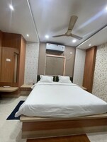 A modern bedroom with a large bed, wooden wardrobe, and an air conditioning unit.