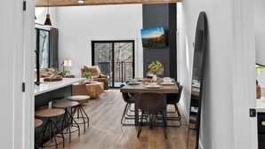 Una cocina moderna con comedor, piso de madera y un televisor grande montado en la pared.
