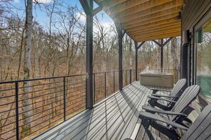A covered deck with Adirondack chairs and a hot tub, overlooking a forested area. - Sleeps 10, Private Heated Indoor Pool, Hot Tub, Shuffleboard, 10 Mi to Dollywood (Sevierville)