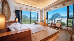 Un dormitorio moderno con una cama grande, muebles de madera, vistas a montañas y un balcón.