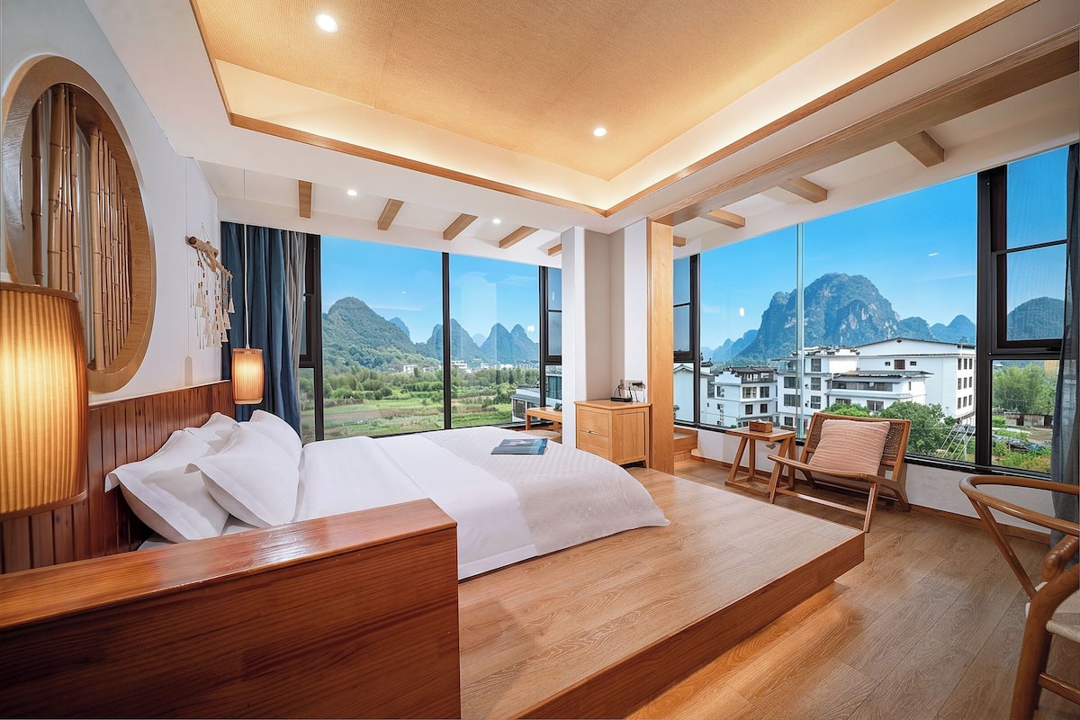 Un dormitorio moderno con una cama grande, muebles de madera, vistas a montañas y un balcón.