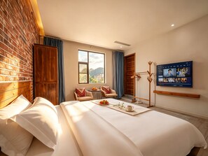 A hotel room with a bed, a TV, a coat rack, and a view of the outdoors. - Yangshuo Floral Whisper Valley (Guilin)