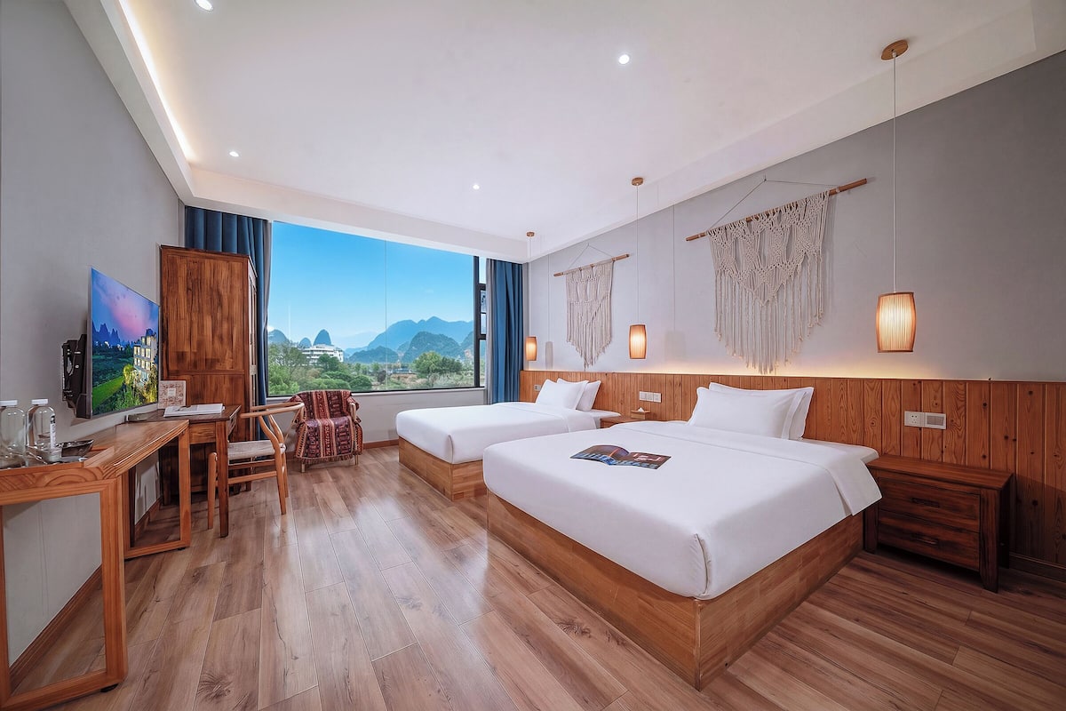 Habitación de hotel con dos camas, un escritorio, una silla, un televisor y vistas a las montañas.