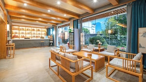Un vestíbulo amplio con muebles de madera, un mostrador de recepción y ventanas grandes que ofrecen vistas al exterior.