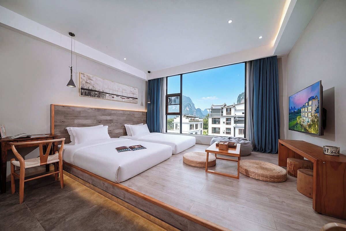 Una habitación de hotel moderna con una cama grande, un escritorio, una silla, una mesita y un televisor.