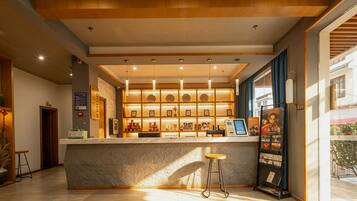 A hotel lobby with a reception desk, a seating area, and a wall with framed pictures.
