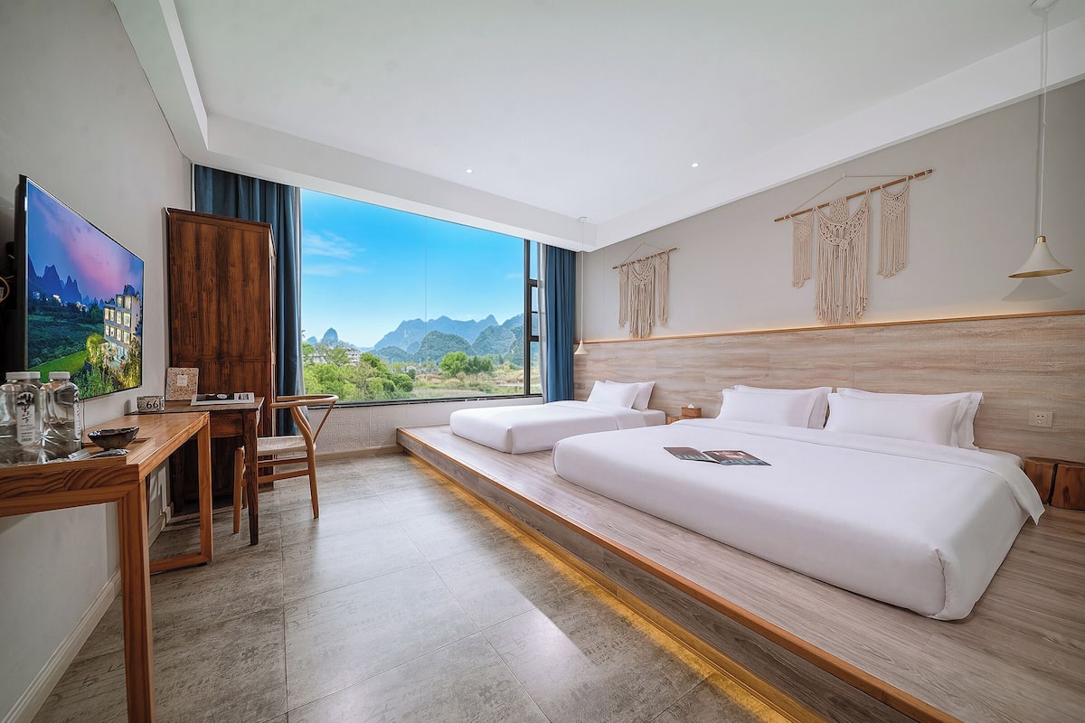 Una habitación de hotel moderna con una cama grande, un escritorio y vistas a las montañas.