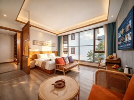 Una habitación de hotel moderna con una cama grande, un sofá, una mesa de comedor y un televisor montado en la pared.