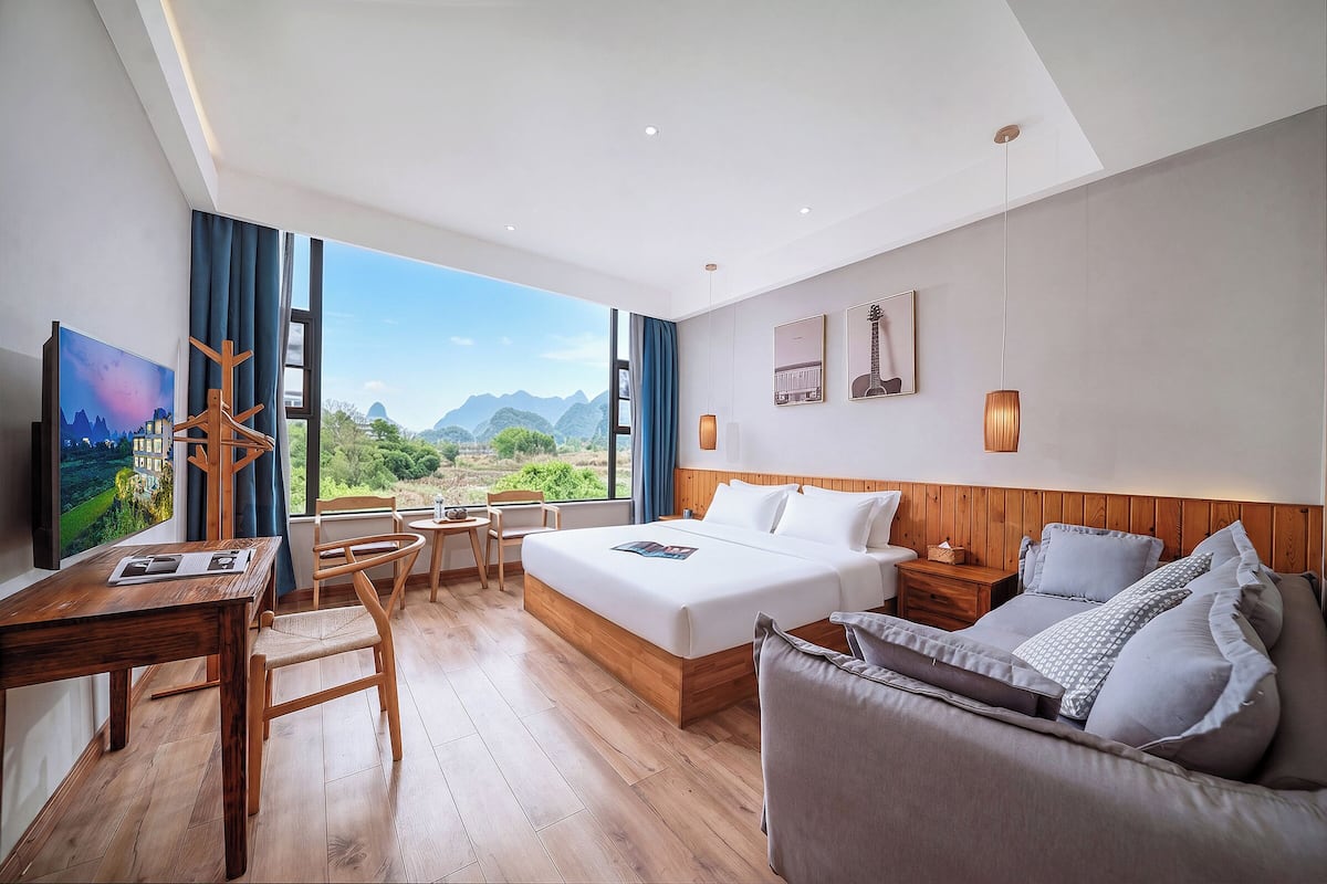 Una habitación de hotel con cama, sofá, escritorio y televisión.