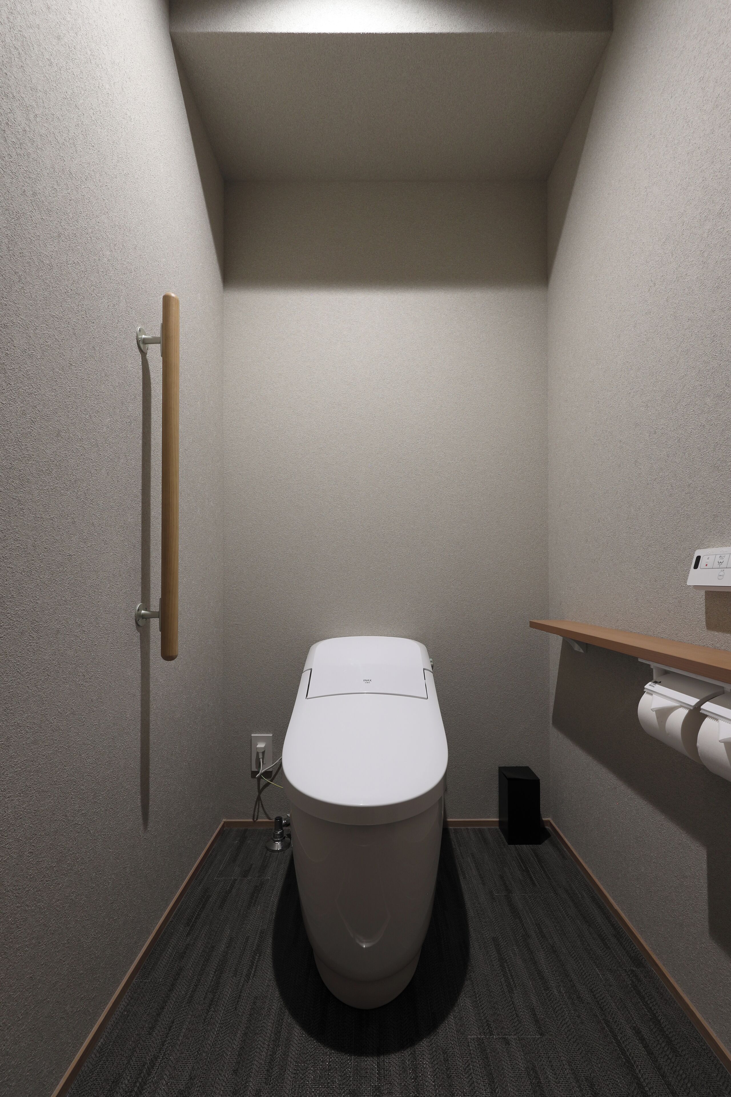 Un bagno piccolo con il water, uno scaffale di legno e un porta carta igienica fissato alla parete.