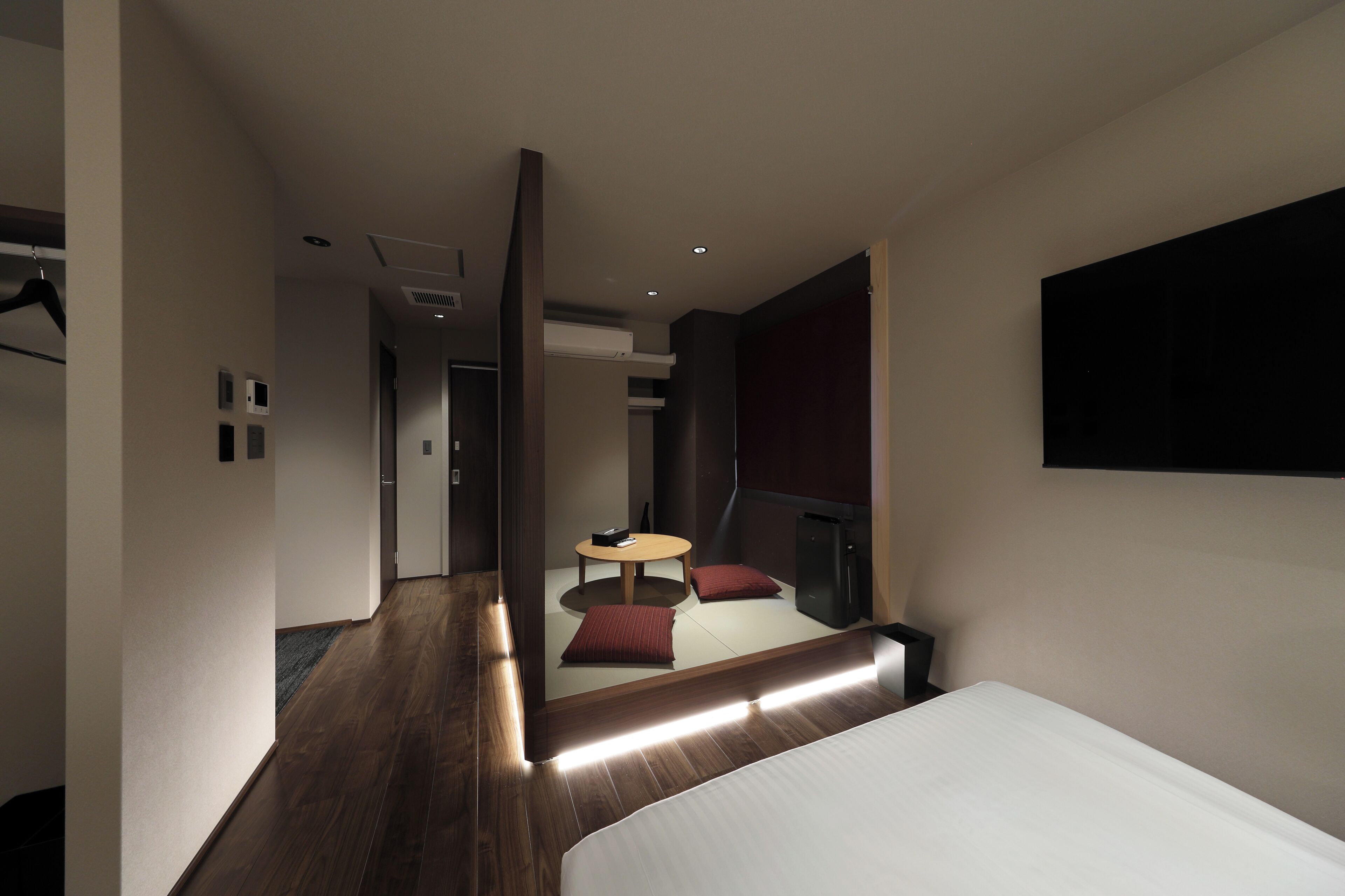 Ein modernes Hotelzimmer mit einem Bett, einem kleinen Tisch mit Stühlen, einem Spiegel und einem Fernseher.