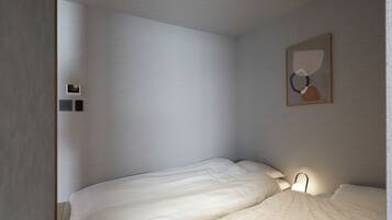 Una habitación pequeña con una cama individual, pared lisa, una lámpara en el techo y un cuadro enmarcado.