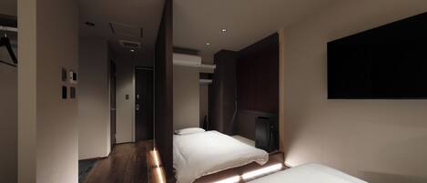 A modern hotel room with two beds, a flat-screen TV, and a built-in fireplace.
