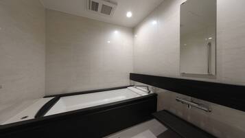 A modern bathroom with a bathtub, a mirror, and a shower.