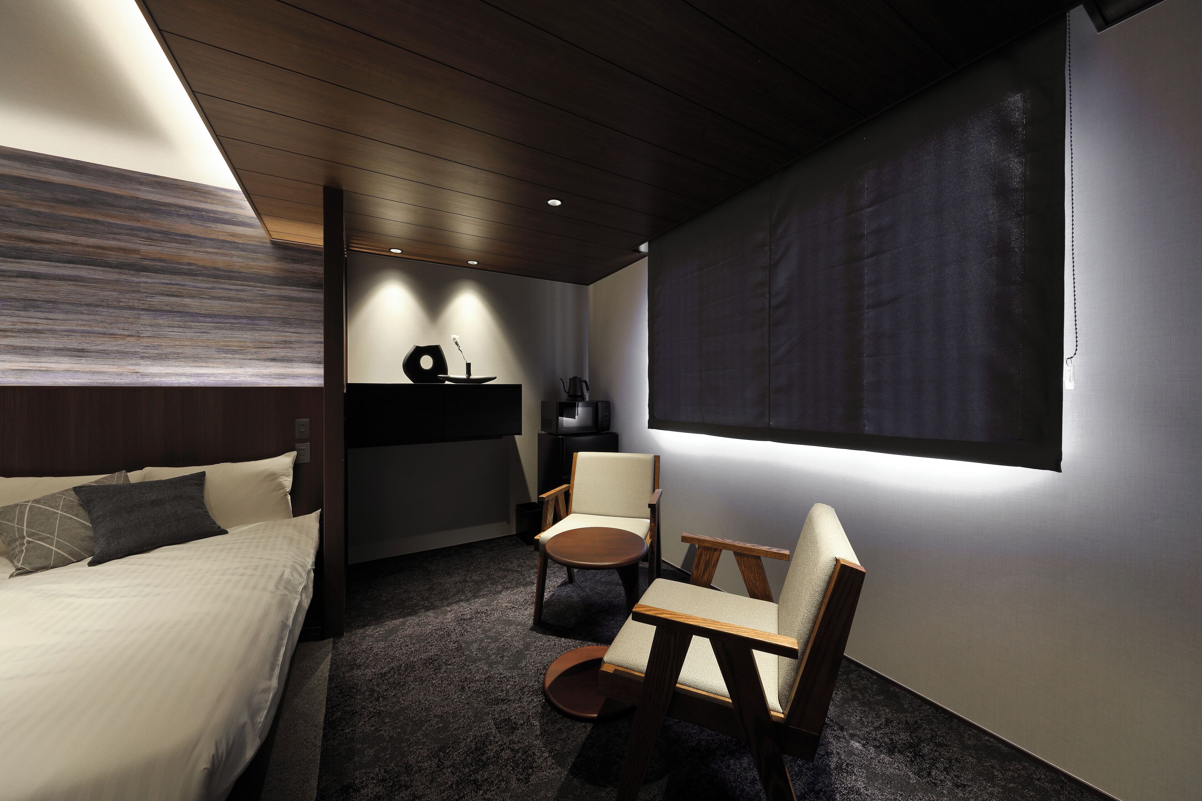 Une chambre d’hôtel moderne équipée d’un lit, d’un bureau, d’une chaise et d’une grande fenêtre.