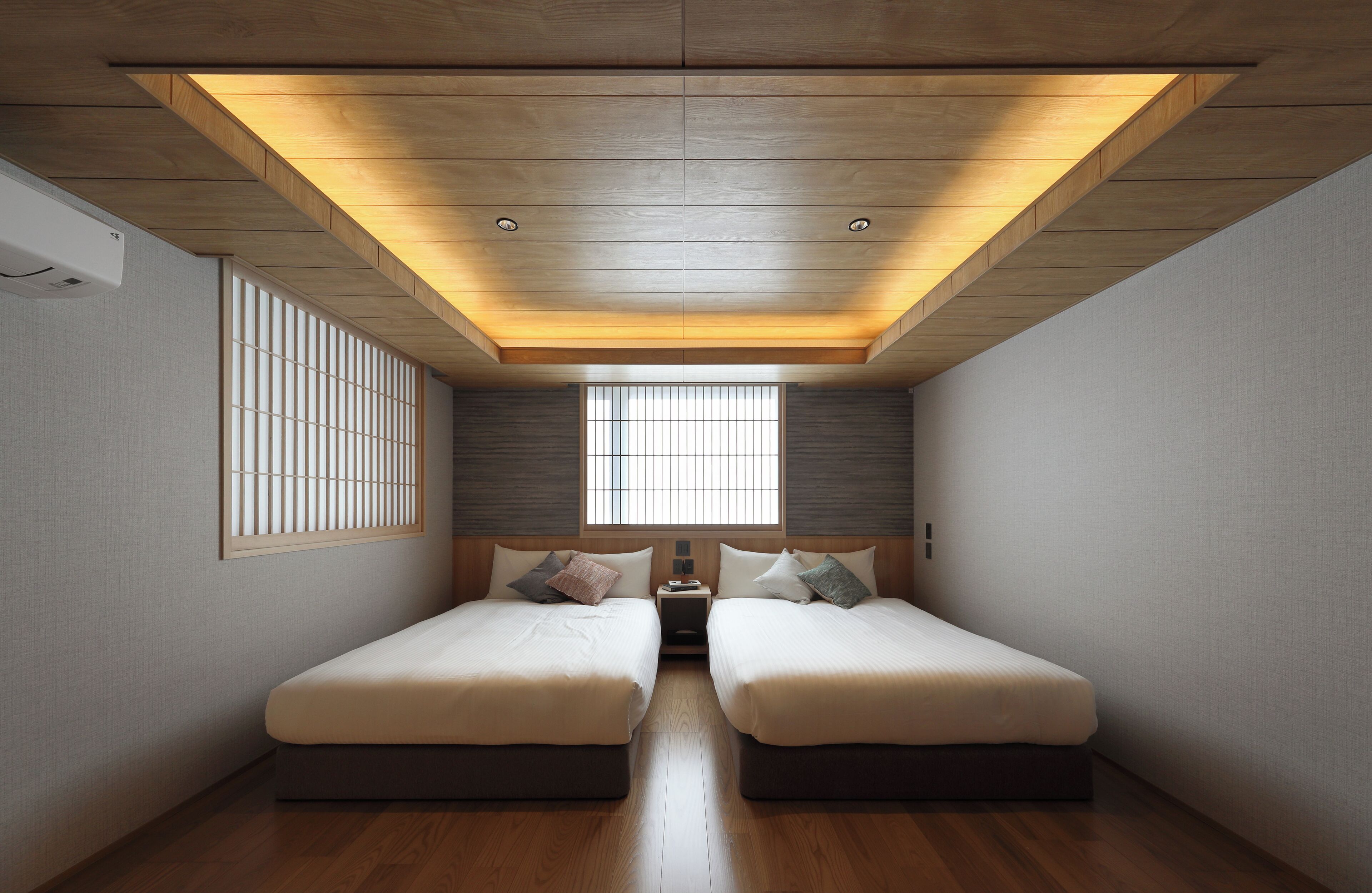 A room with two beds, a skylight, a window, and a nightstand.