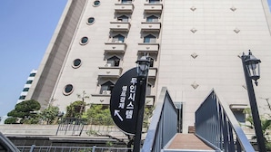 Un immeuble de grande hauteur, doté de nombreux balcons et d’une enseigne indiquant une direction.