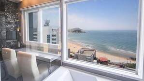 Une chambre moderne dotée d’une grande fenêtre donnant sur une plage et l’océan.