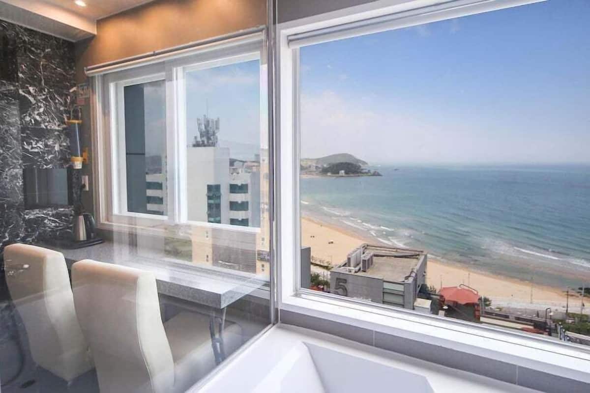 A modern room with a large window overlooking a beach and ocean.