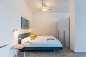 Ein modernes Schlafzimmer mit Bett, Nachttisch und Deckenventilator.