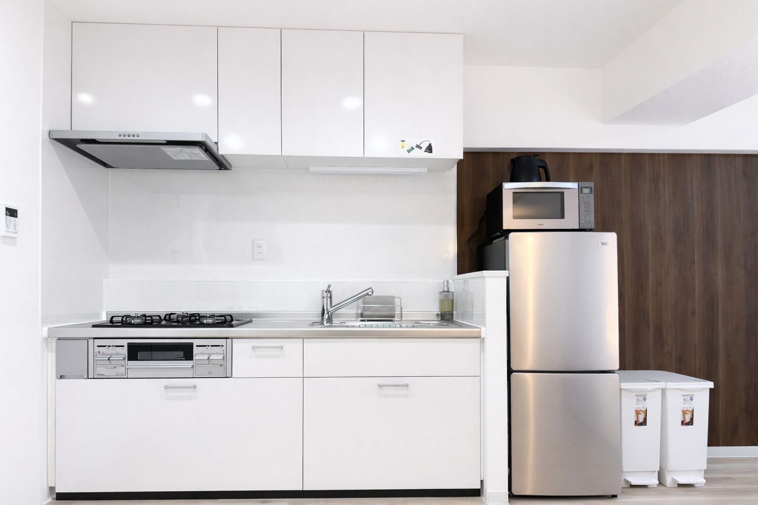 A modern kitchen with white cabinetry, a stainless steel refrigerator, a microwave, and a dishwasher.