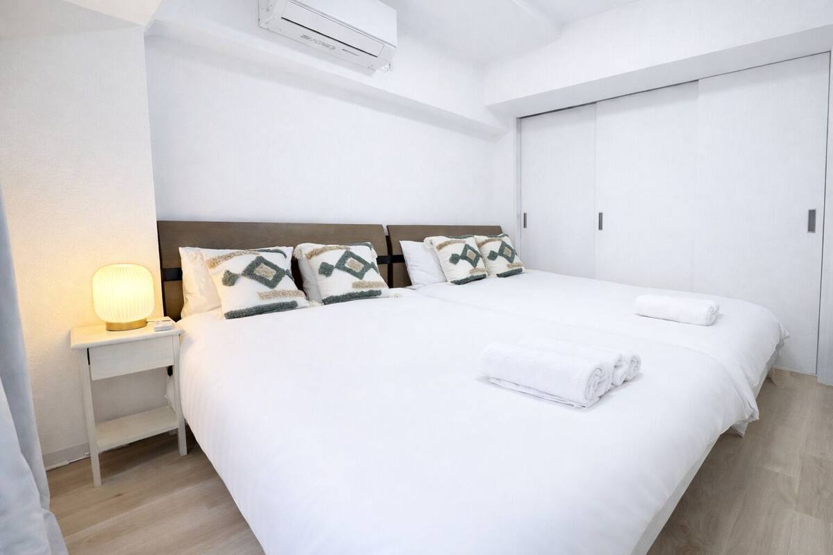 A hotel room with a large bed, a bedside table with a lamp, and a wardrobe.