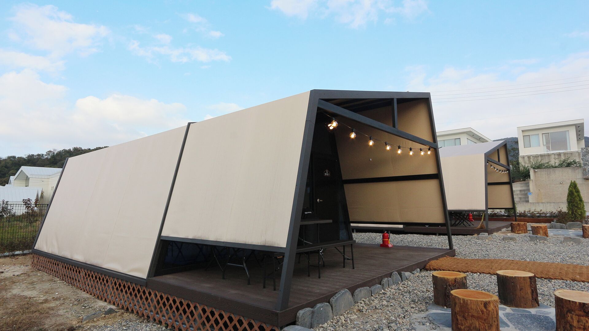 A modern, minimalist outdoor structure with a flat roof and a wooden deck.