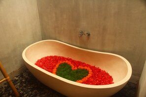 A bathtub filled with red and green pebbles arranged in a heart shape. - Arena Villa Ubud (Ubud)
