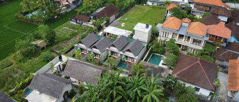 Vista aérea de um bairro residencial com casas, piscina e vegetação exuberante.