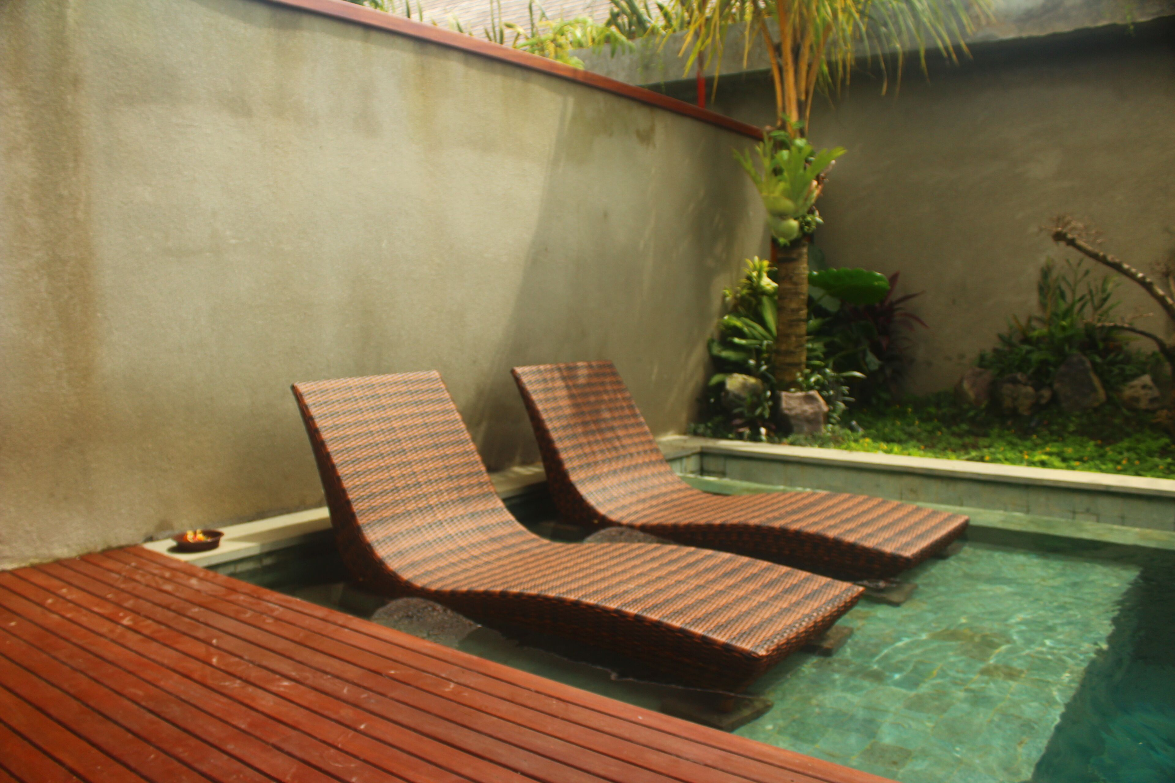 A pool area with two lounge chairs and a wooden deck.