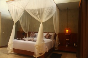 A bedroom with a four-poster canopy bed, a bedside table with a lamp, and a small nightstand with a vase of flowers. - Arena Villa Ubud (Ubud)