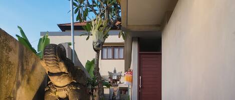 A staircase leading to a red door, surrounded by potted plants and a stone wall.