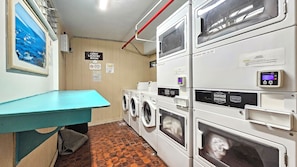 A laundry room with multiple washing machines, a blue bench, and a wall-mounted sign indicating a guest laundry room. - Aloha Surf 706 — Central Waikiki Queen Studio-Suite w/Sofa-Bed&Kitchen ⁂Sleeps 3 (Honolulu)