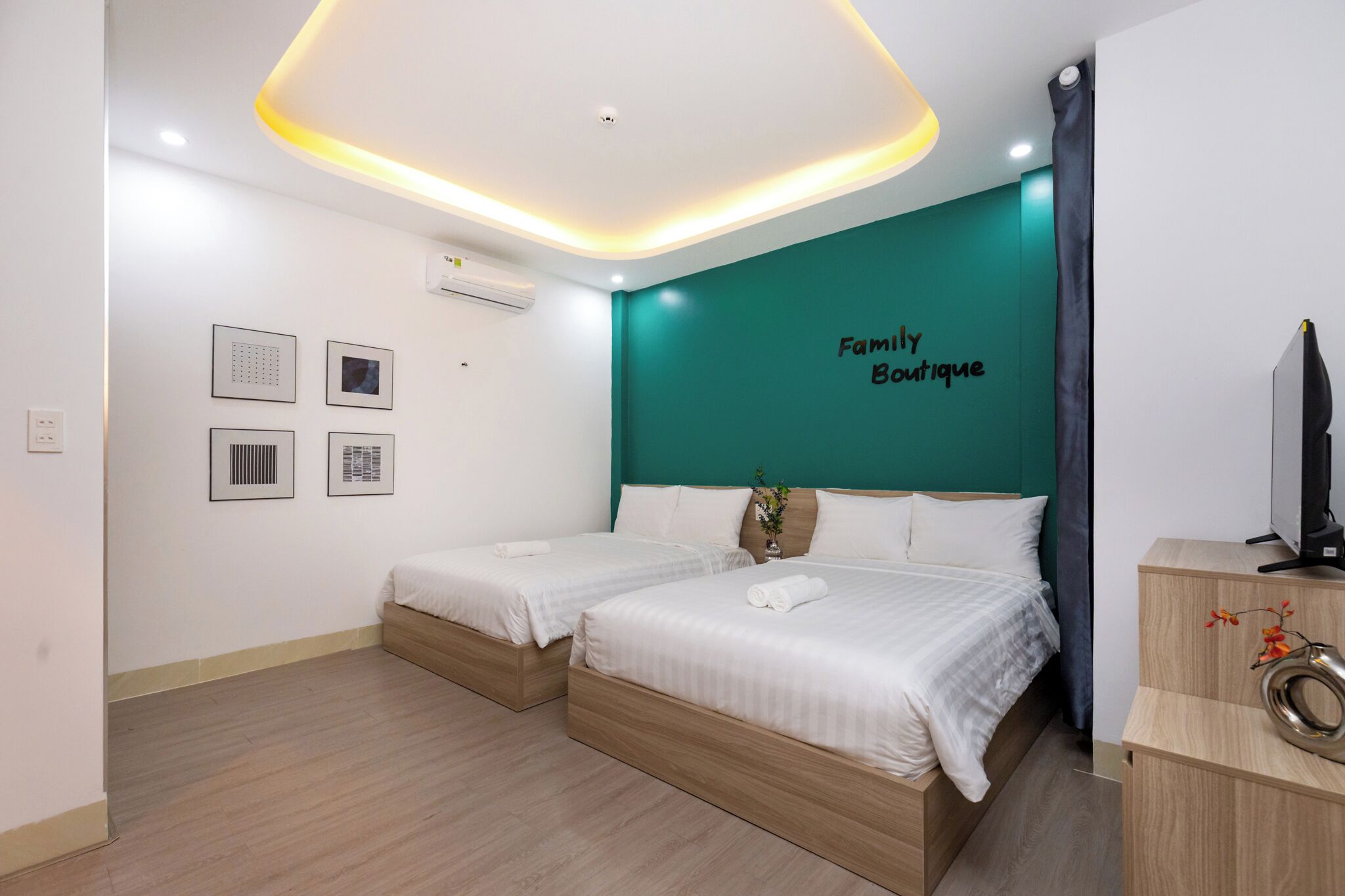 A hotel room with two beds, a teal accent wall, and a 'Family Boutique' sign.