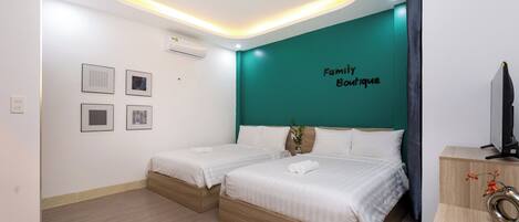 A hotel room with two beds, a teal accent wall, and a 'Family Boutique' sign.