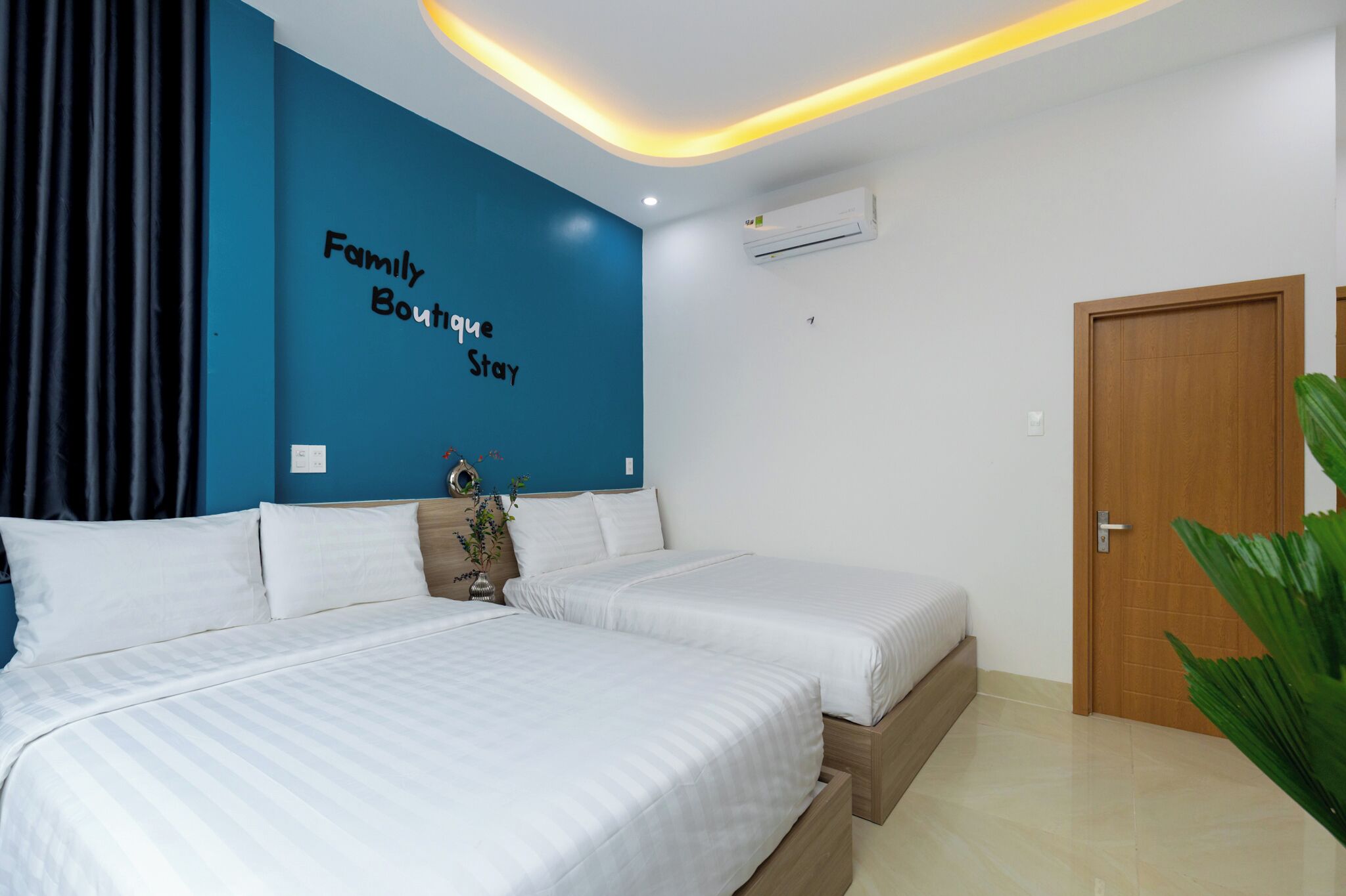 A hotel room with a large bed, a blue accent wall, and a wooden door.