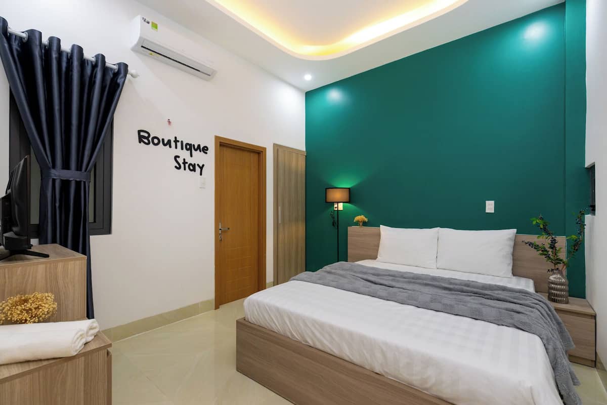 A modern bedroom with a bed, a nightstand, a lamp, and a wall-mounted air conditioner.