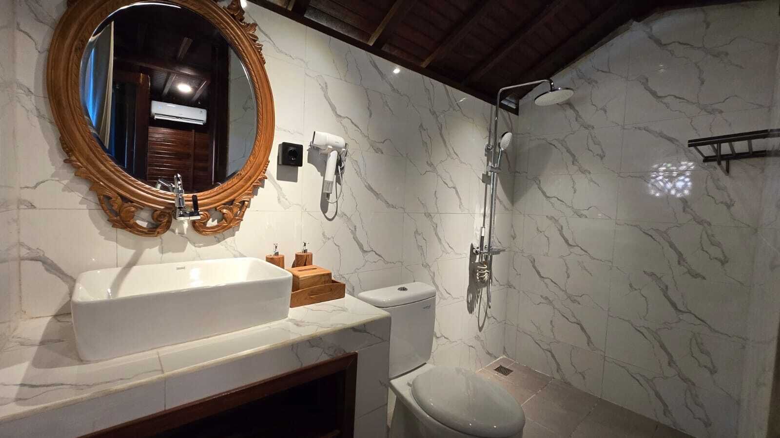 A bathroom with a marble vanity, a freestanding toilet, and a shower enclosure.