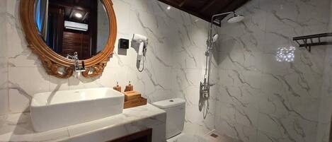 A bathroom with a marble vanity, a freestanding toilet, and a shower enclosure.