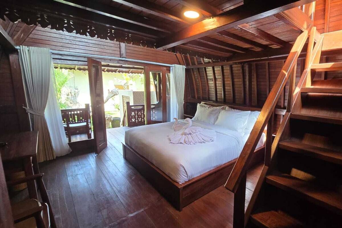 A wooden bedroom with a bed, a staircase, and a balcony.