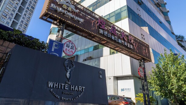 Een hoog gebouw met een bord waarop 'The White Hart' en 'Brightly' staan, op de begane grond.
