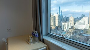 Hotelkamer met een tafel bij een raam, een stoel en een dienblad met flessen en glazen.
