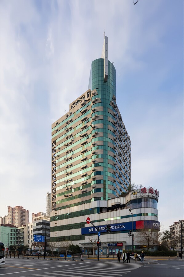 A modern high-rise building with a curved facade, multiple air conditioning units, and a prominent sign at the top. - Shanghai Tongrenge Guesthouse (Shanghai)