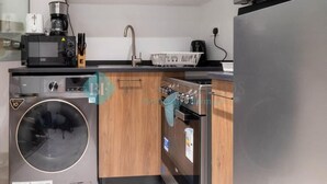 Una cocina compacta con microondas, cafetera y electrodomésticos de acero inoxidable.