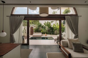Un interior moderno con piscina, zona de estar y vista a un jardín.