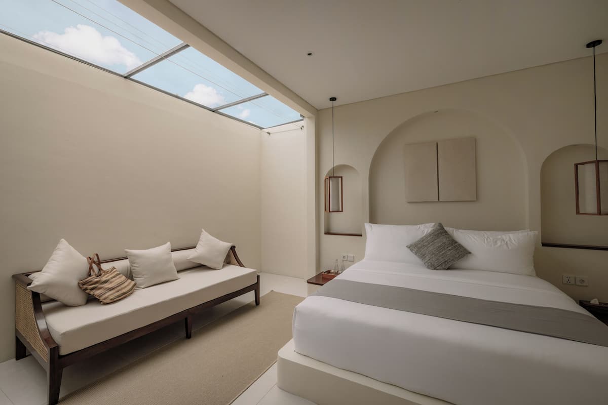 Une chambre à coucher avec un lit, un canapé, une lucarne et une table de chevet.