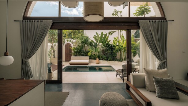 Ein modernes Interieur mit Pool, Sitzgelegenheit und Blick auf einen üppigen Garten.