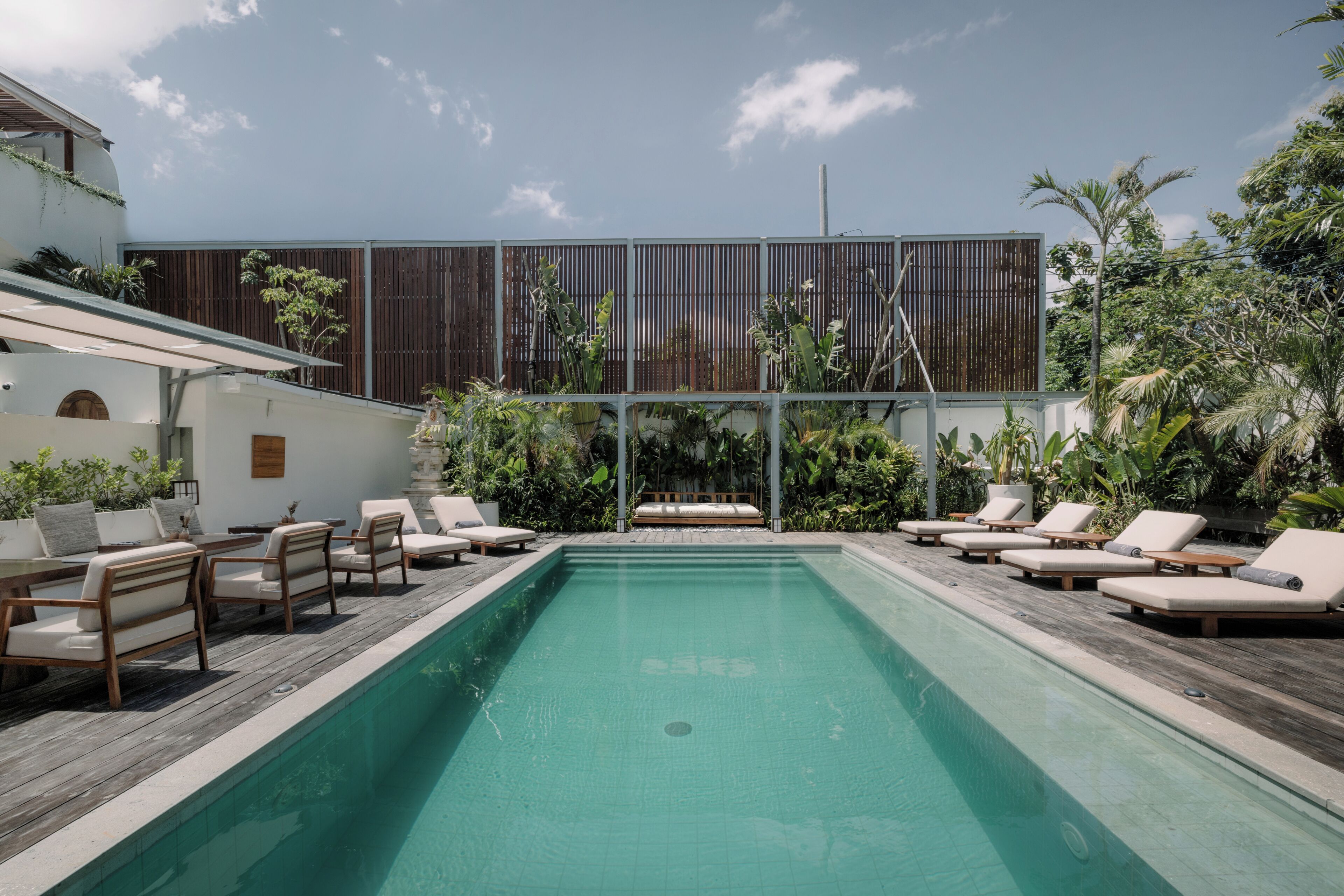 Un área de piscina con sillones de descanso y una terraza de madera.